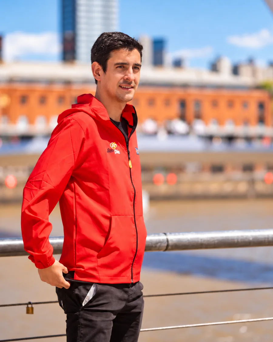 Nico Sappia sonriendo con campera roja junto al Puente de la Mujer